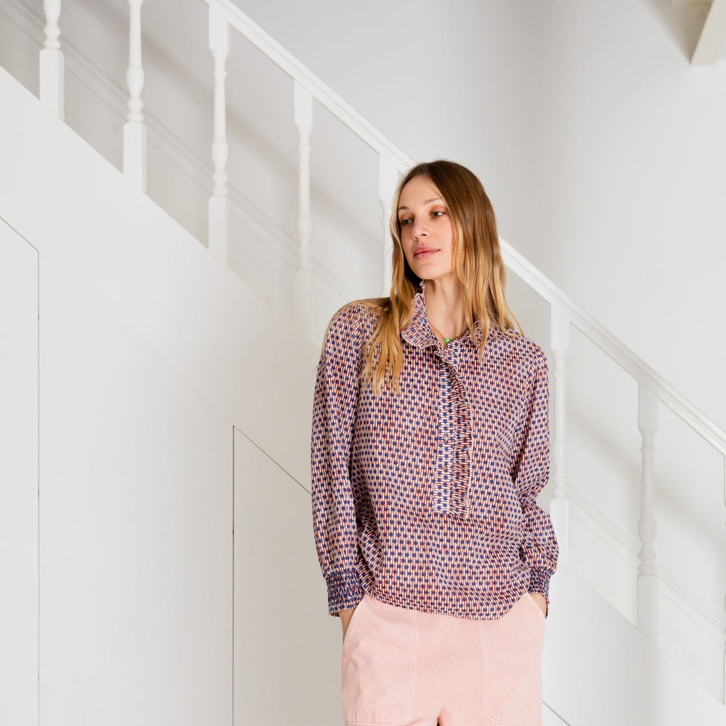 Model wearing a patterned blouse in shades of pink and purple by Bonte, paired with light pink trousers.