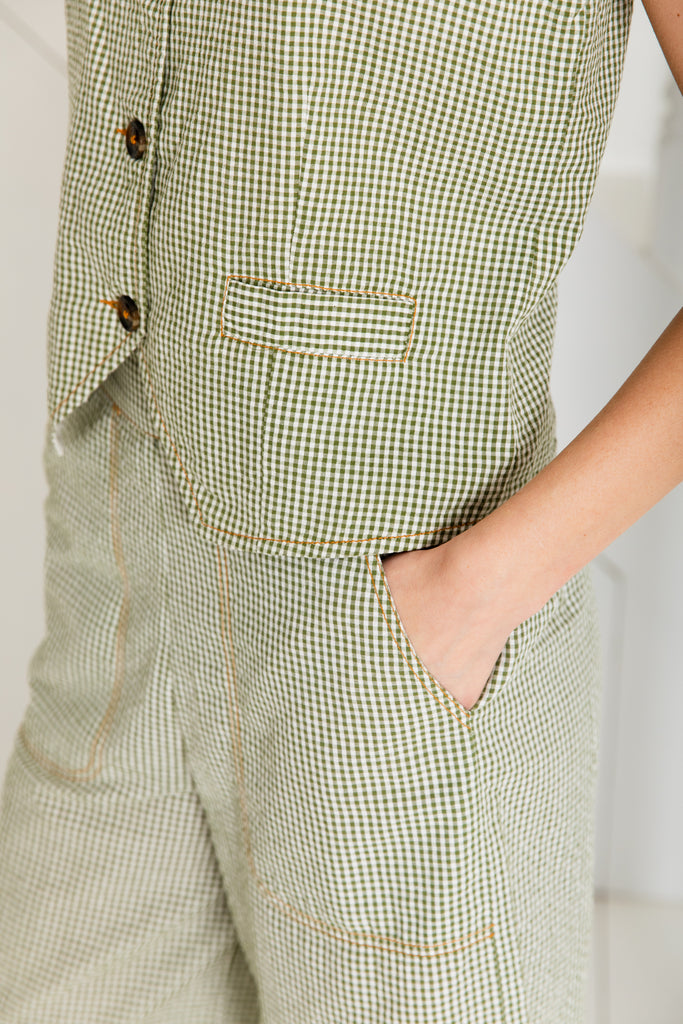 A close-up of a woman wearing a Bonte green and white checkered outfit with contrast stitching and a pocket.