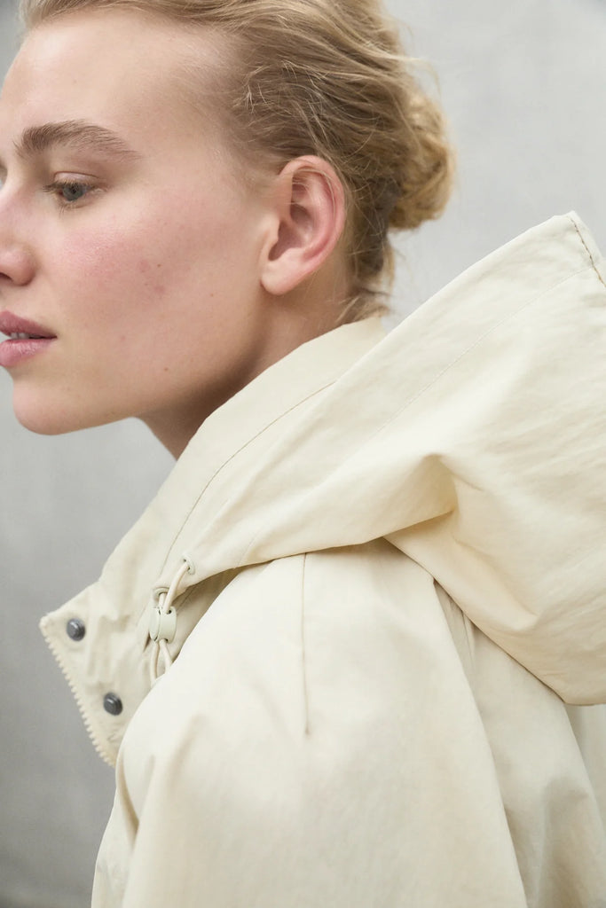 Close-up of a person wearing a light beige Ecoalf jacket with an accentuated hood.