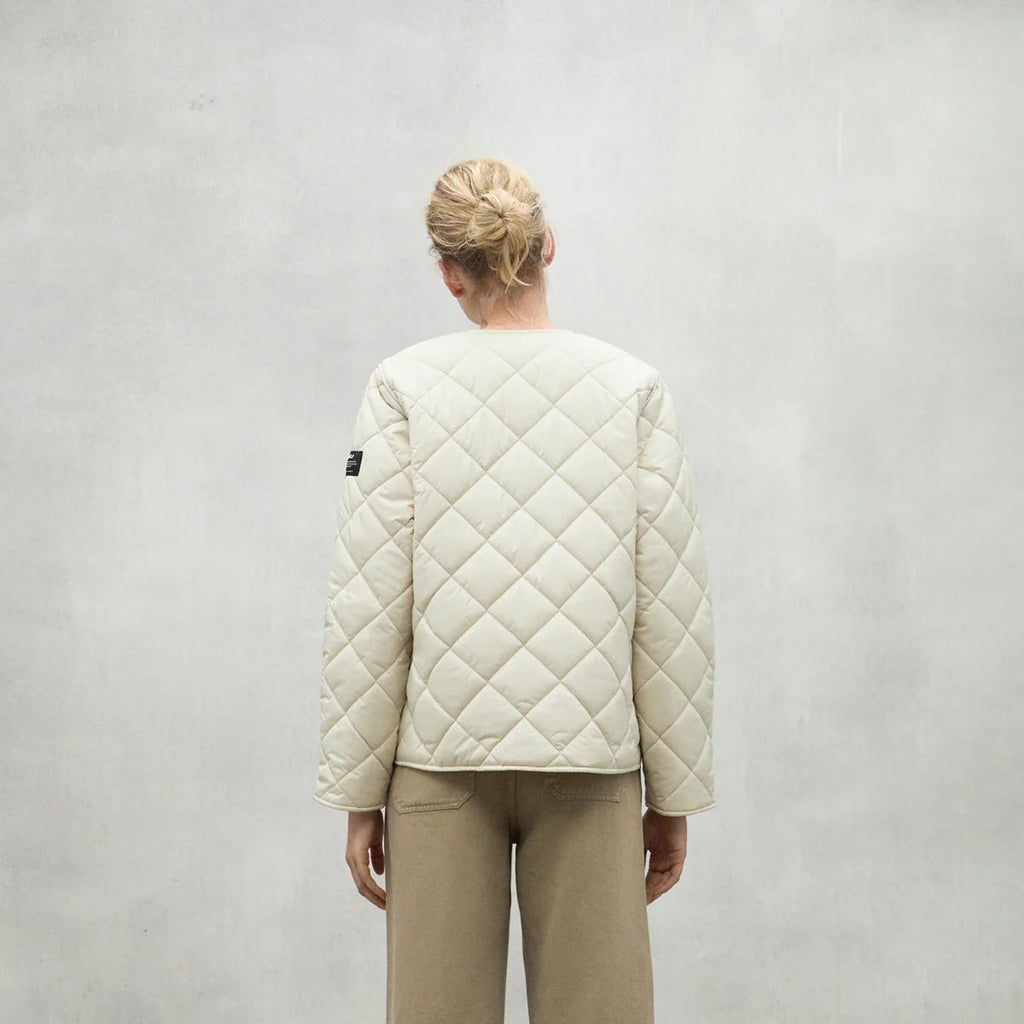 A person stands with their back to the camera, wearing a beige Ecoalf quilted jacket and light tan pants.