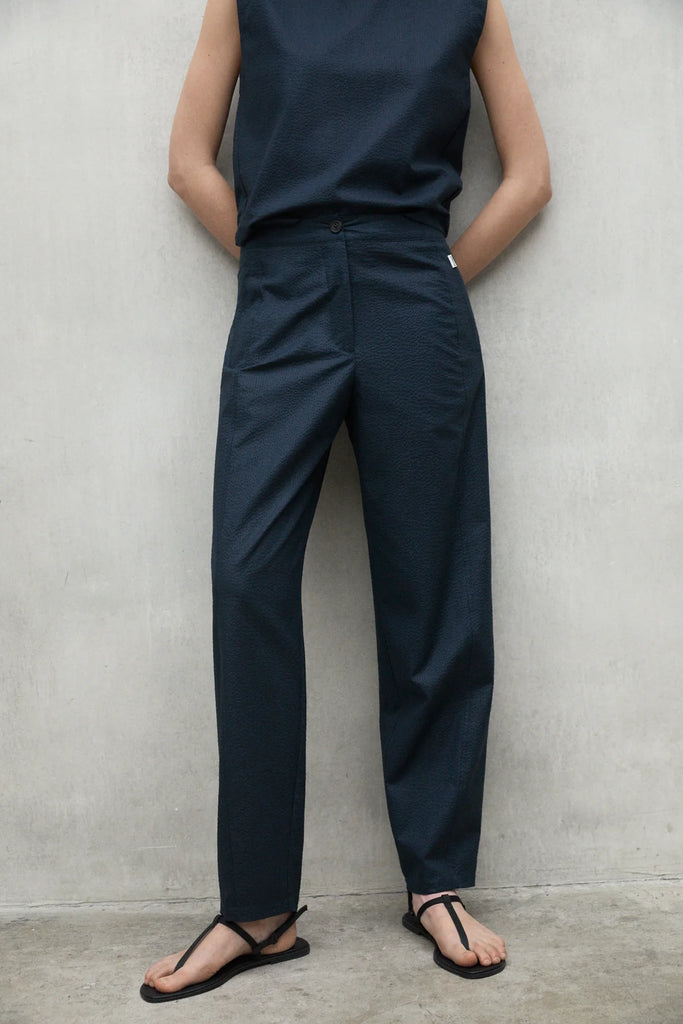 Model wears a dark blue Ecoalf sleeveless top and matching trousers, paired with black sandals.