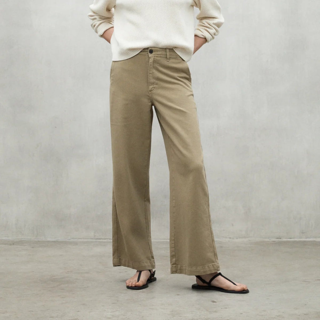 Person wearing a cream Ecoalf sweater and khaki wide-leg pants, paired with black flip-flops on a concrete background.