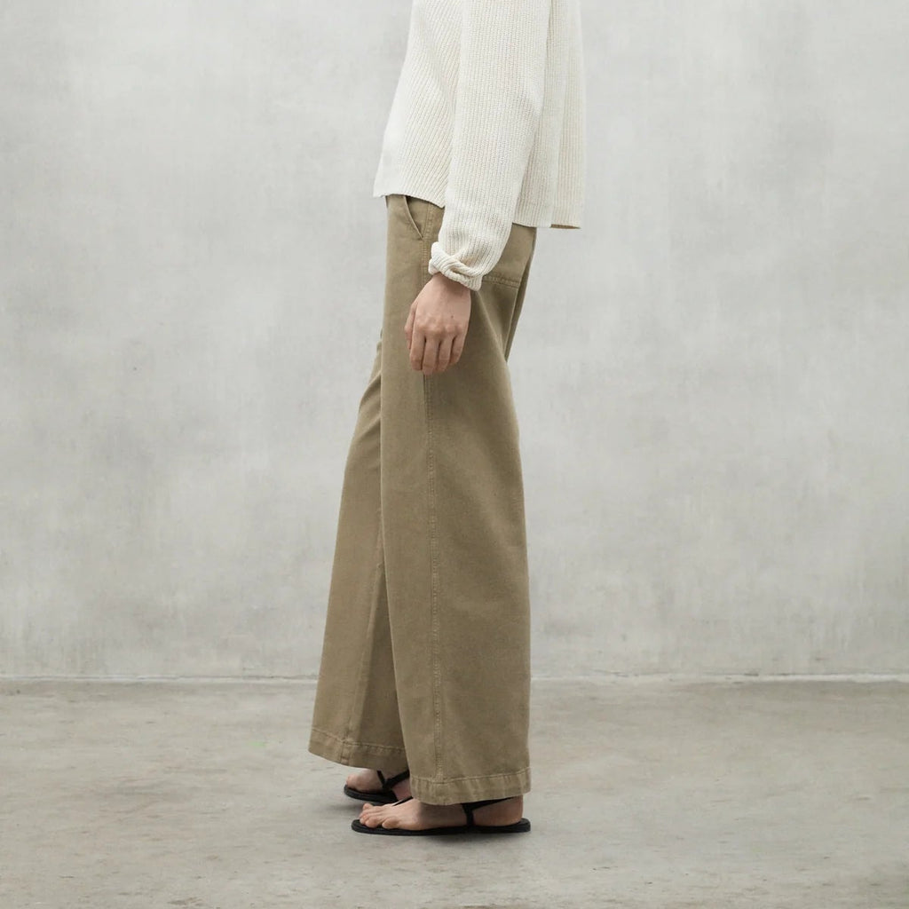 A person with a white ribbed top and khaki wide-leg pants from Ecoalf, standing on a concrete floor.