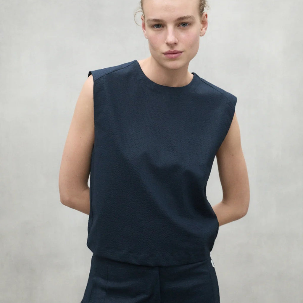 Model wearing a navy sleeveless top from Ecoalf, with a minimalist style against a neutral background.