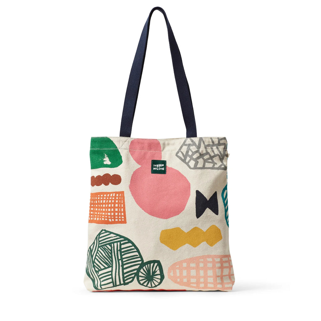 Canvas tote bag by Donna Wilson, featuring navy handles and colorful patterns in green, pink, orange, and black.